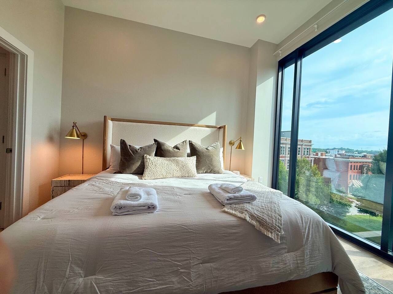 Ett hotellrum med en stor säng, utsikt över staden och en modern design.
