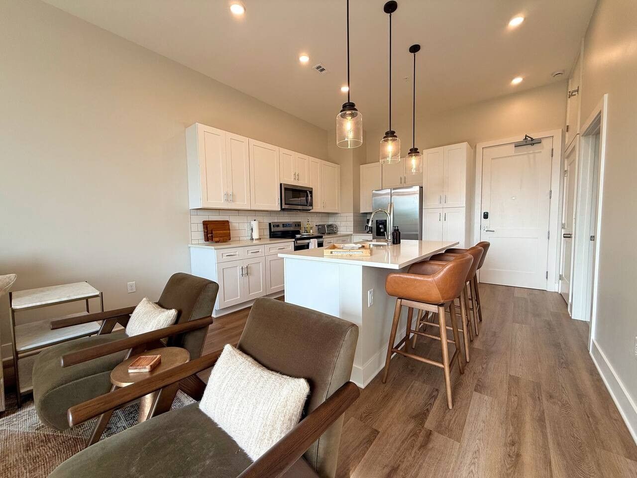 A modern kitchen with white cabinets, a central island, and pendant lighting.