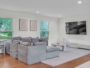 Ein modernes Wohnzimmer mit einer Eckcouch, einem Couchtisch und einem flachbildfernseher, der an der Wand befestigt ist.