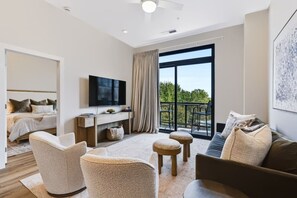 Une chambre d’hôtel moderne équipée d’un lit, d’une télévision, d’un balcon et d’un coin salon.