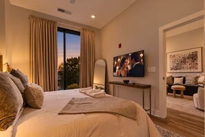 Une chambre d’hôtel avec un grand lit, une télévision, une console et une vue sur l’extérieur.