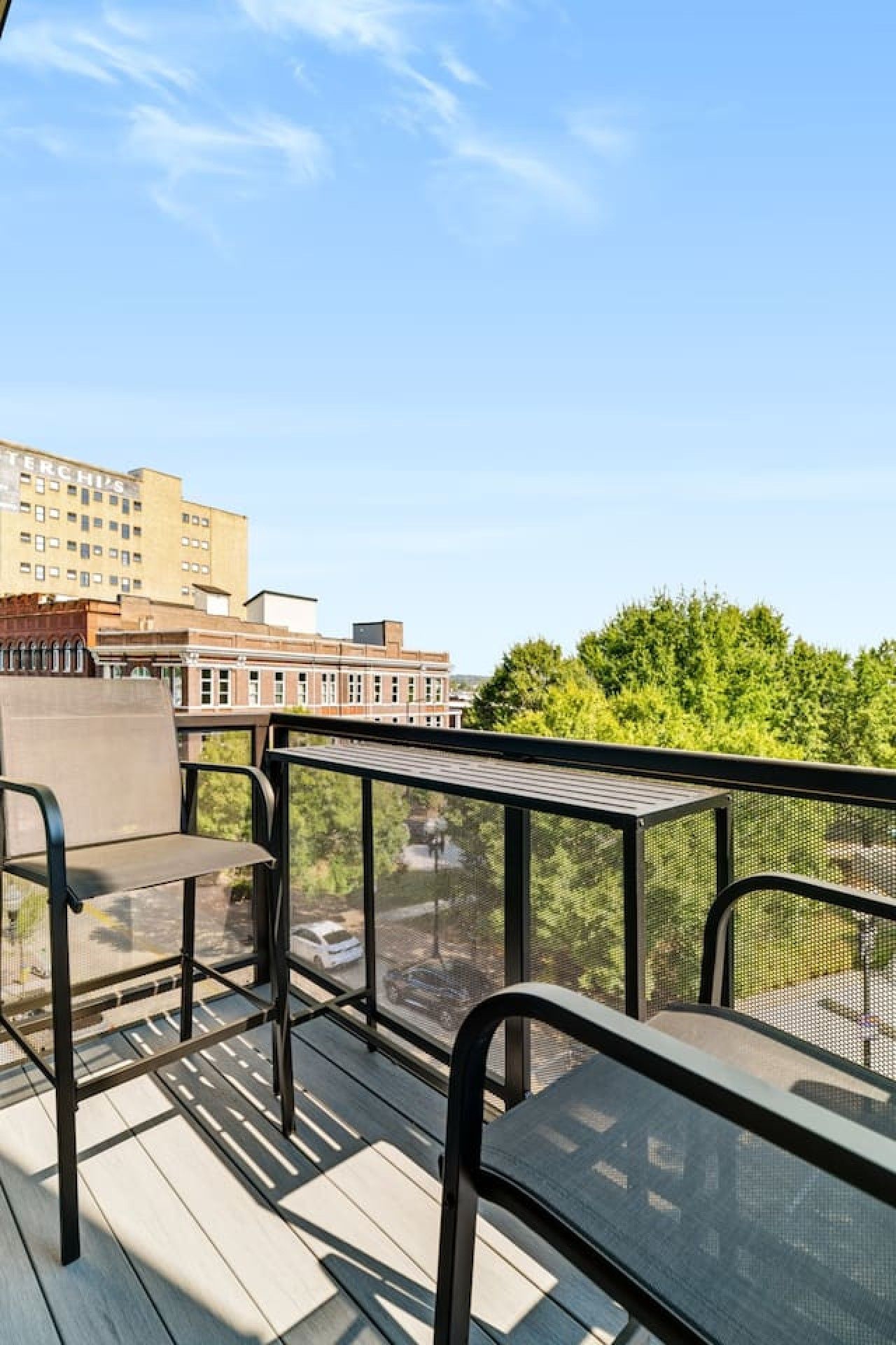 A balcony with outdoor furniture, a clear view of a cityscape, and a building with 'TERCHIPS' signage.