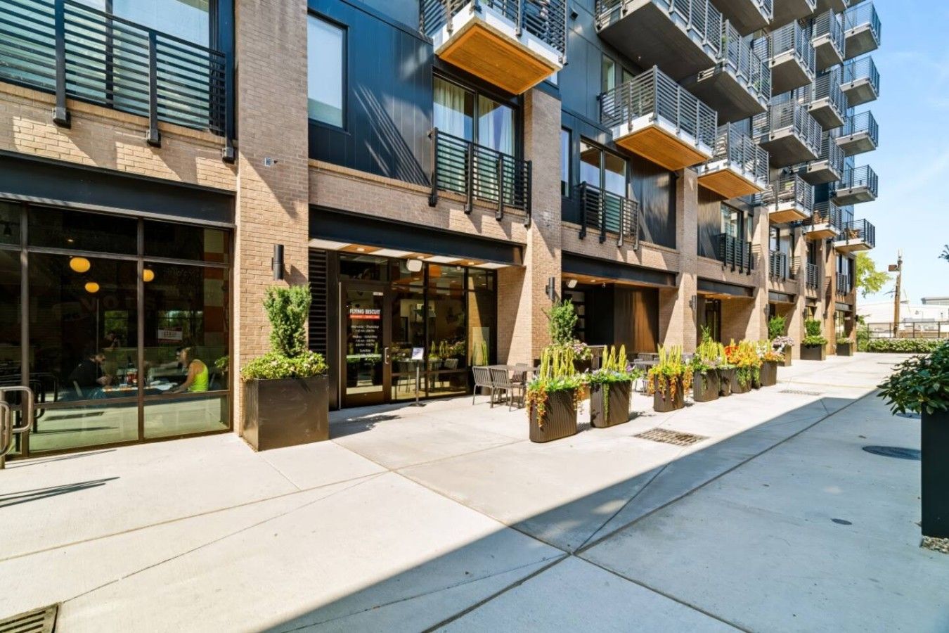 A modern building with outdoor seating and planters.