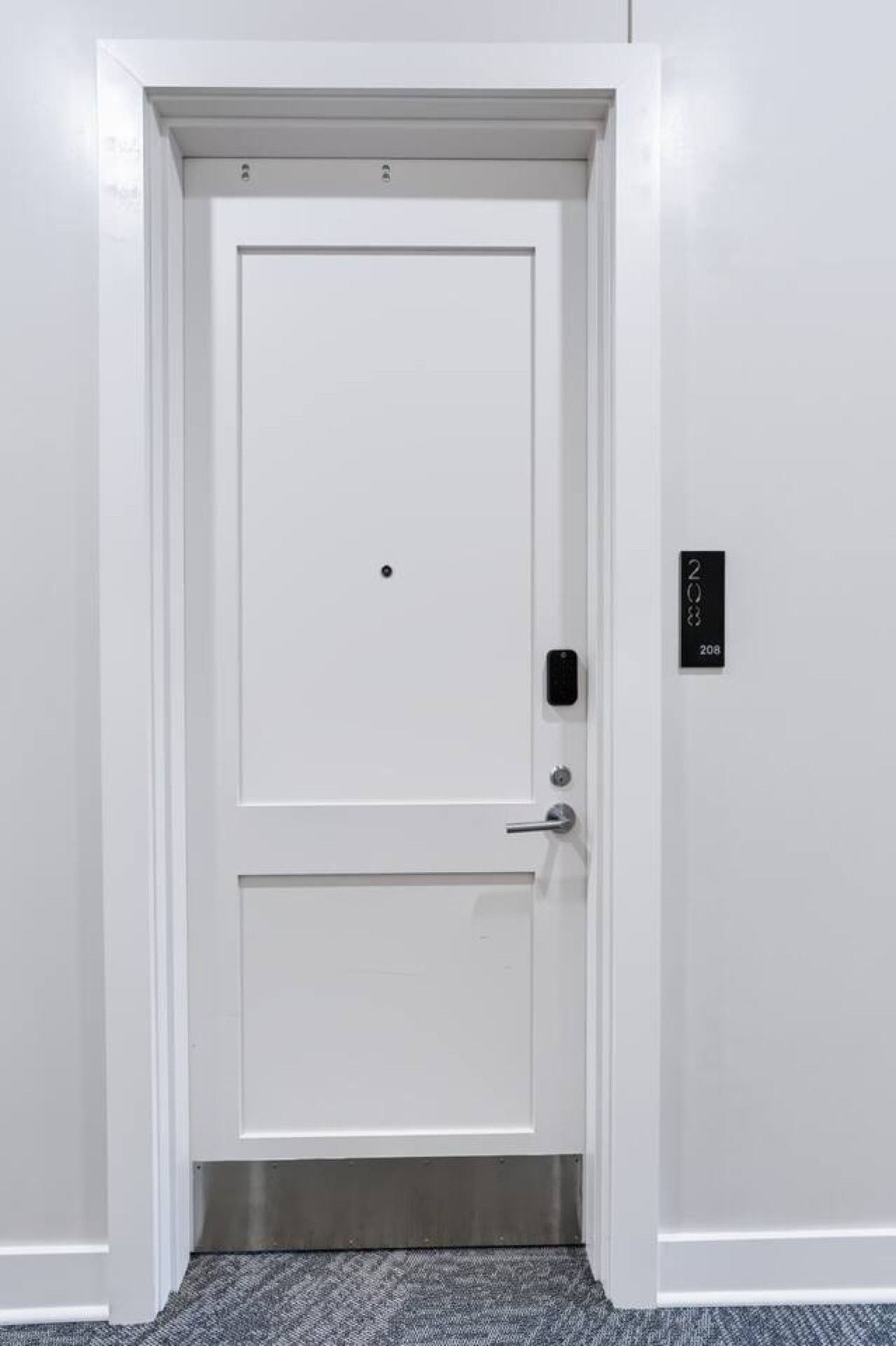 A white door with a keypad lock and a small sign above it.