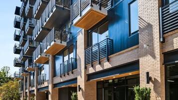 A modern multi-story residential building with balconies, large windows, and outdoor planters.