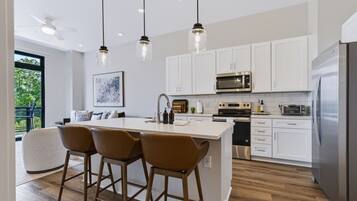 A modern kitchen with white cabinets, stainless steel appliances, and a central island with bar stools.