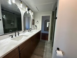 A modern bathroom with a large vanity, dual sinks, and a walk-in shower. - City Views & Comfort | Heart of Downtown Knoxville (Knoxville)