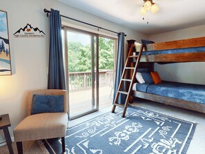 A room with a bunk bed, a chair, a ladder, a large window, and a door leading to an outdoor deck. - Powdered Sugar at Shallowford Walk (Sugar Mountain)