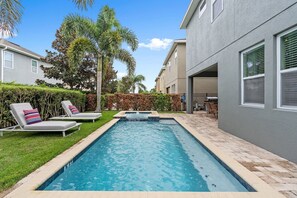 A rectangular swimming pool with a 5 FT depth marker, surrounded by a brick patio, with lounge chairs and a small waterfall feature. - 6BR Near Disney Private Pool, spa & Loft (Kissimmee)