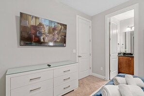 A bedroom with a bed, a dresser, a painting, a door, and a bathroom visible through an open door. - 6BR Near Disney Private Pool, spa & Loft (Kissimmee)