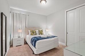 A bedroom with a bed, nightstands, a lamp, a glass table, and a door. - 6BR Near Disney Private Pool, spa & Loft (Kissimmee)