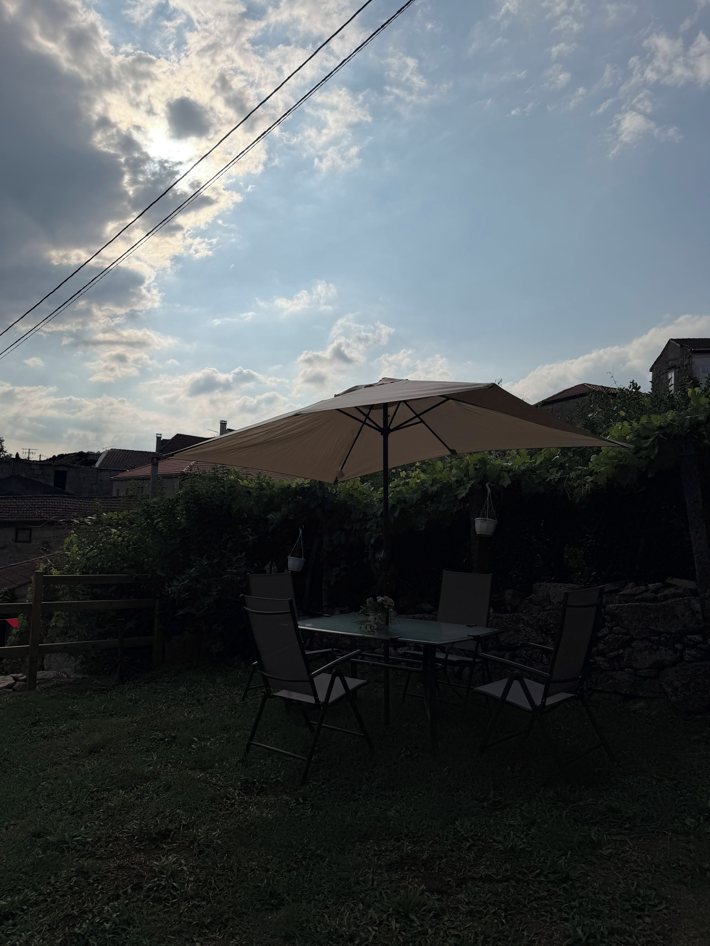 Une terrasse extérieure avec une table et des chaises, un grand parasol et un mur en pierre.