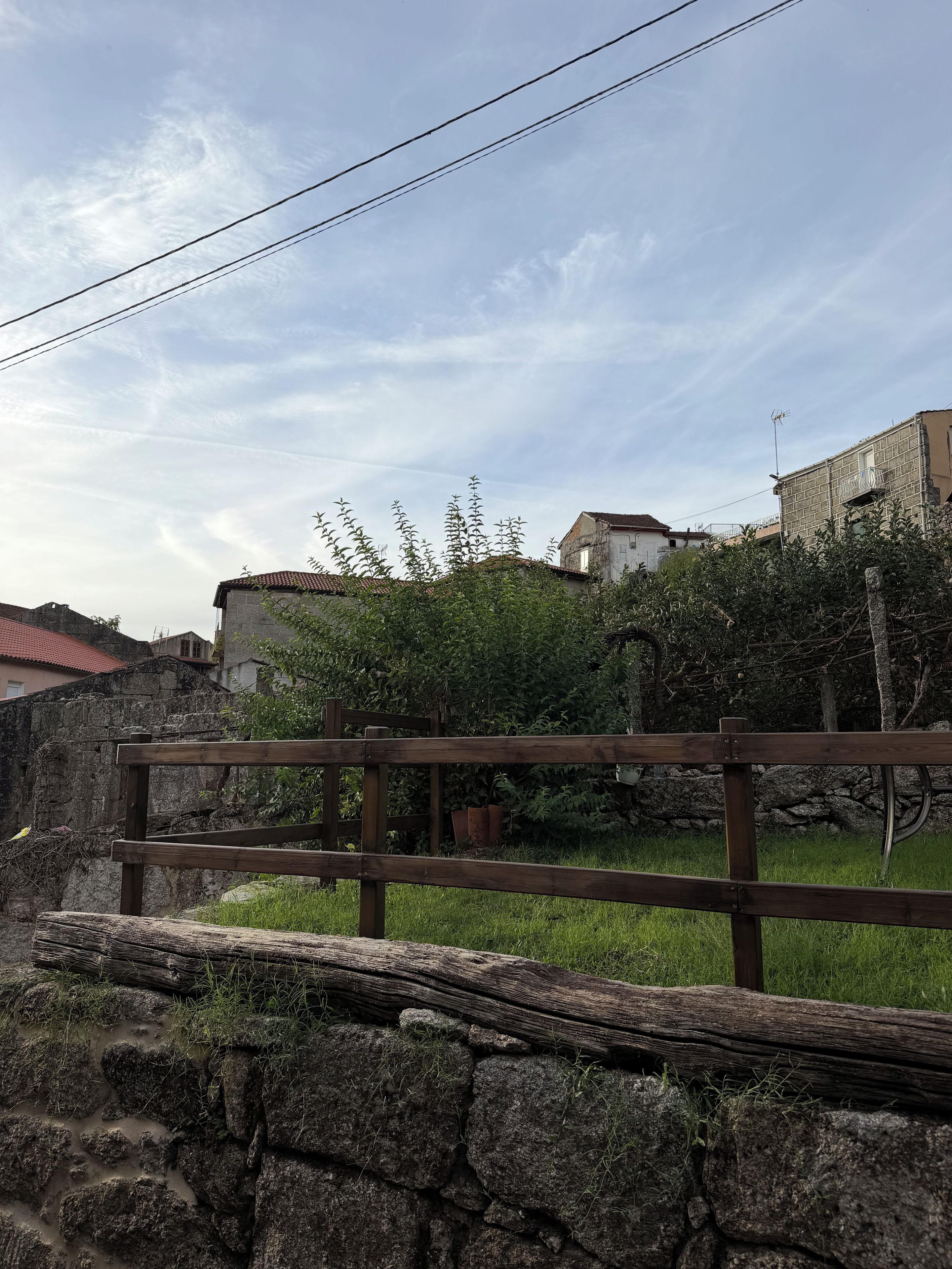 Un mur de pierres avec une clôture en bois au premier plan, un autre mur de pierres en arrière-plan et un ciel dégagé au-dessus.