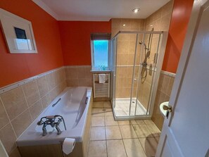 A bathroom with a bathtub, shower, toilet, and a window with blinds. - Airds Hotel (Appin)