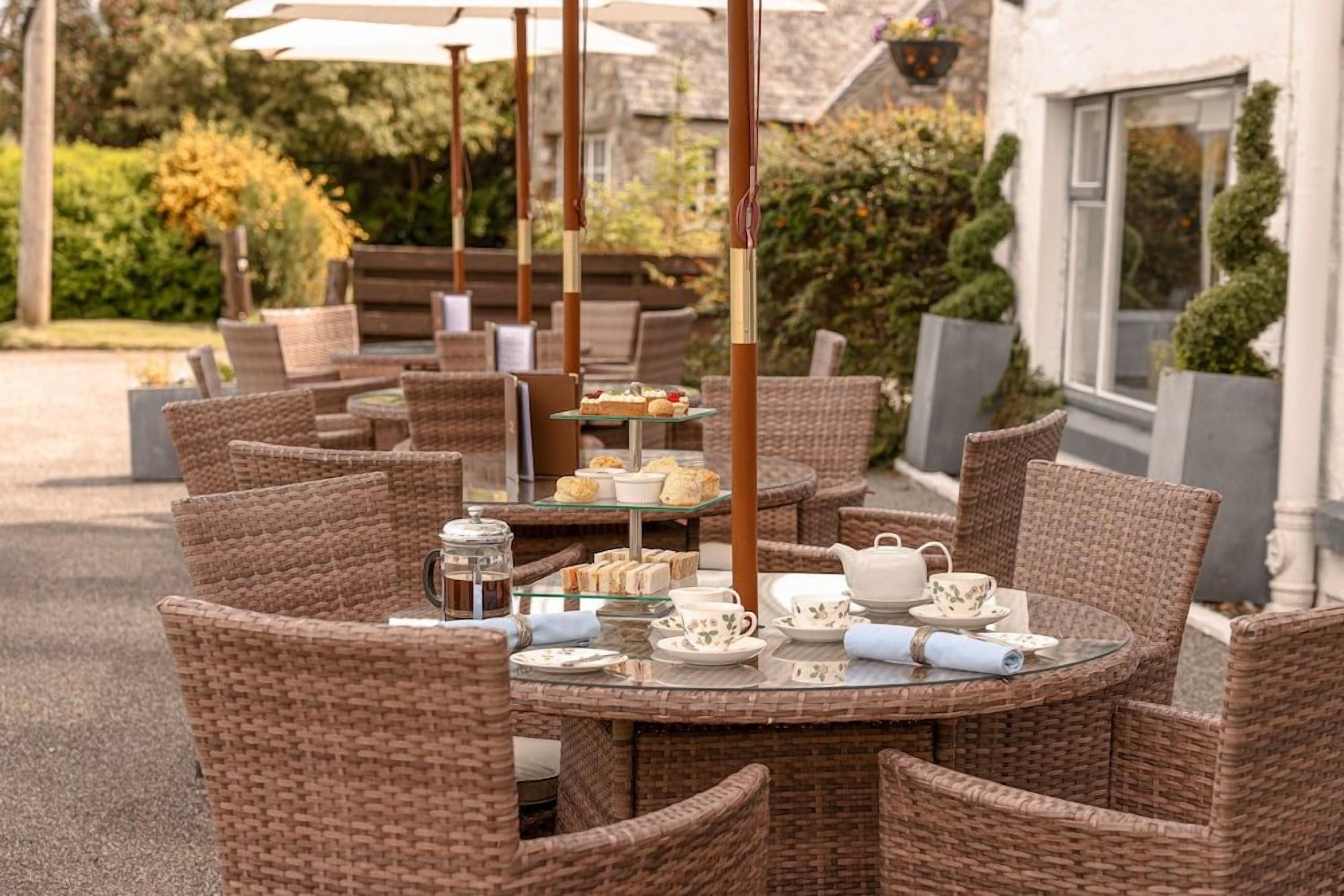 An outdoor seating area with wicker furniture and a tea service setup.