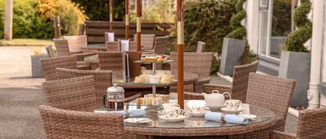 An outdoor seating area with wicker furniture and a tea service setup.