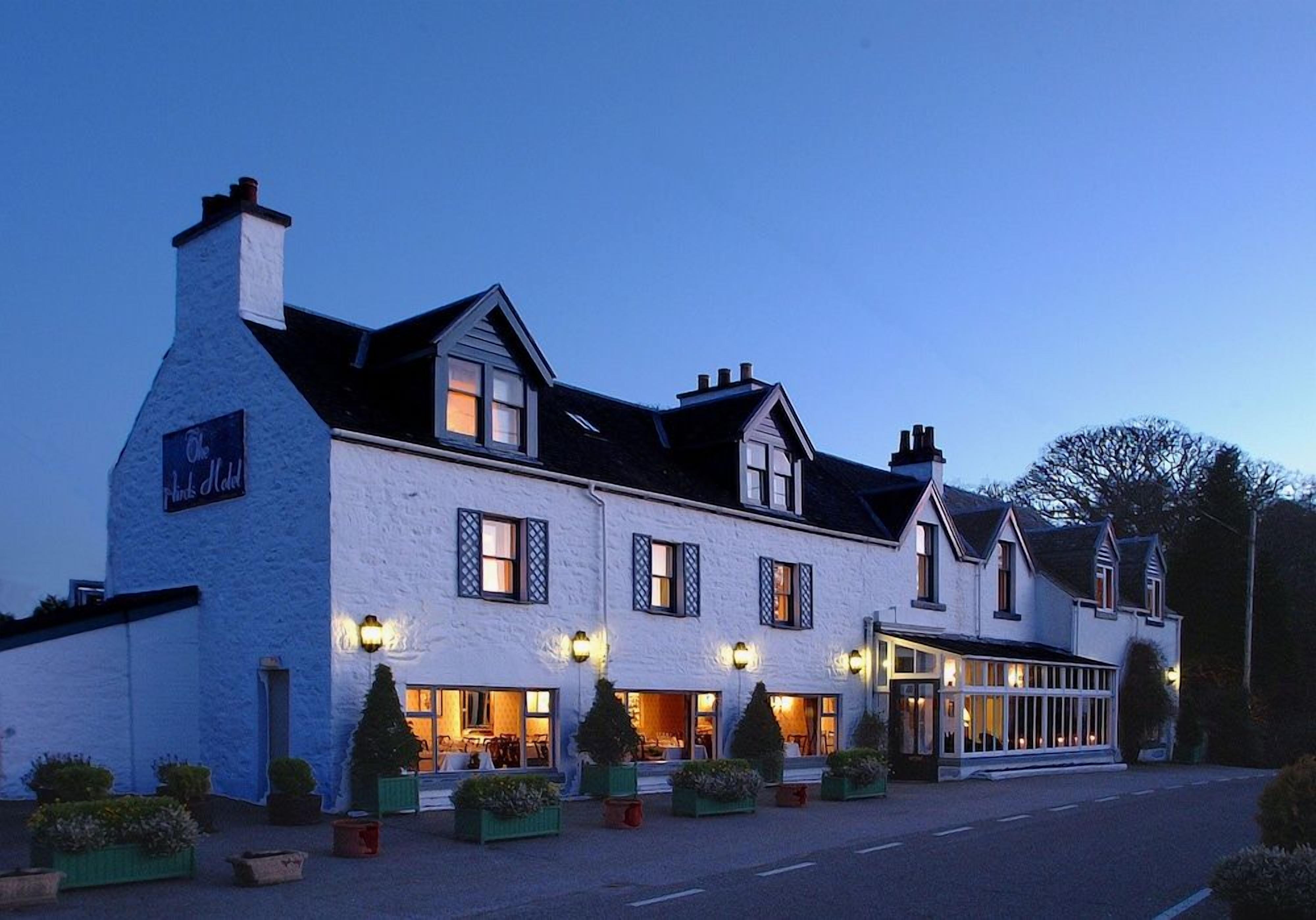 A two-story hotel with a white facade, multiple windows, and a covered entrance area.