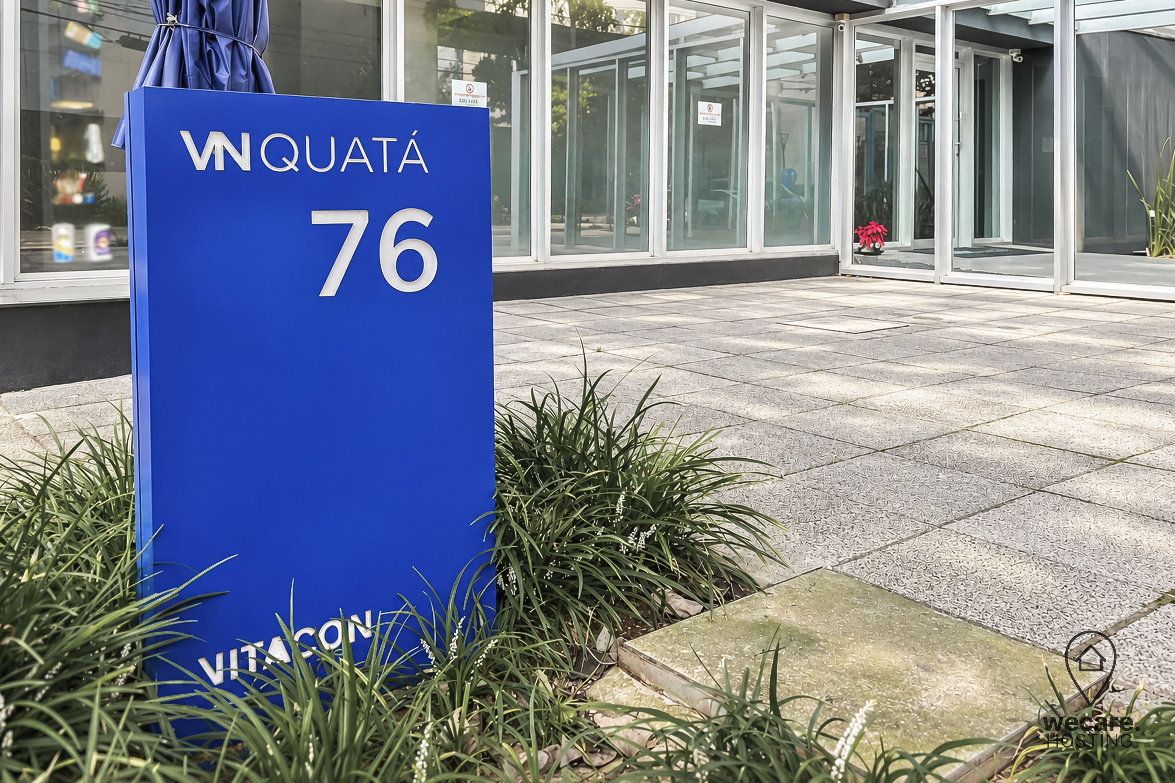 Un letrero azul con el número 76 y el nombre 'VITACON', señalización de un hotel o propiedad.