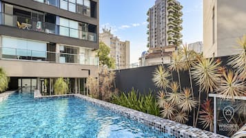 Um edifício moderno com piscina, cercado por plantas.