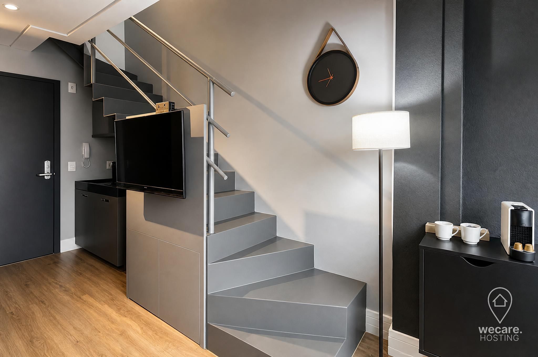 Une chambre d’hôtel moderne équipée d’un escalier, d’un téléviseur à écran plat, d’une lampe et d’un coin café.