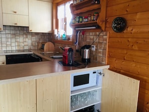 A compact kitchen with wooden cabinets, a built-in microwave, and a coffee maker. - Clarossa Appartement/Fewo, Dusche oder Bad, WC 6-Bettwohnung by Interhome (Bellwald)