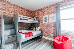 A bunk bed with a red blanket, a grey dresser, and a red bean bag chair in a room with brick walls and a window. - 6BR Near Disney Private Pool, spa & Game Room (Kissimmee)