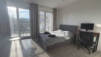 Un dormitorio con cama, escritorio, silla y televisor.