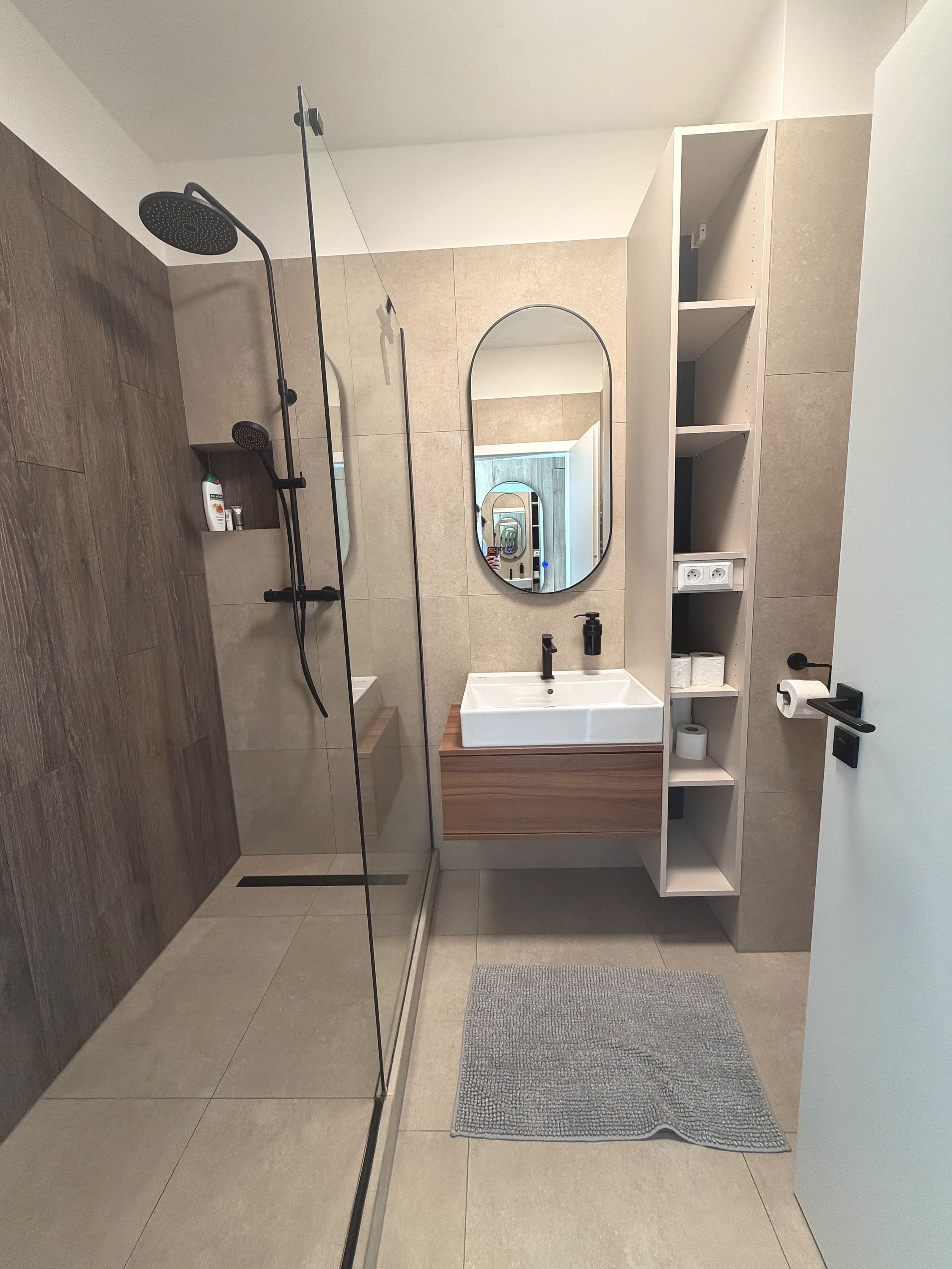 Un baño moderno con cabina de ducha de vidrio, un lavamanos blanco y un espejo.
