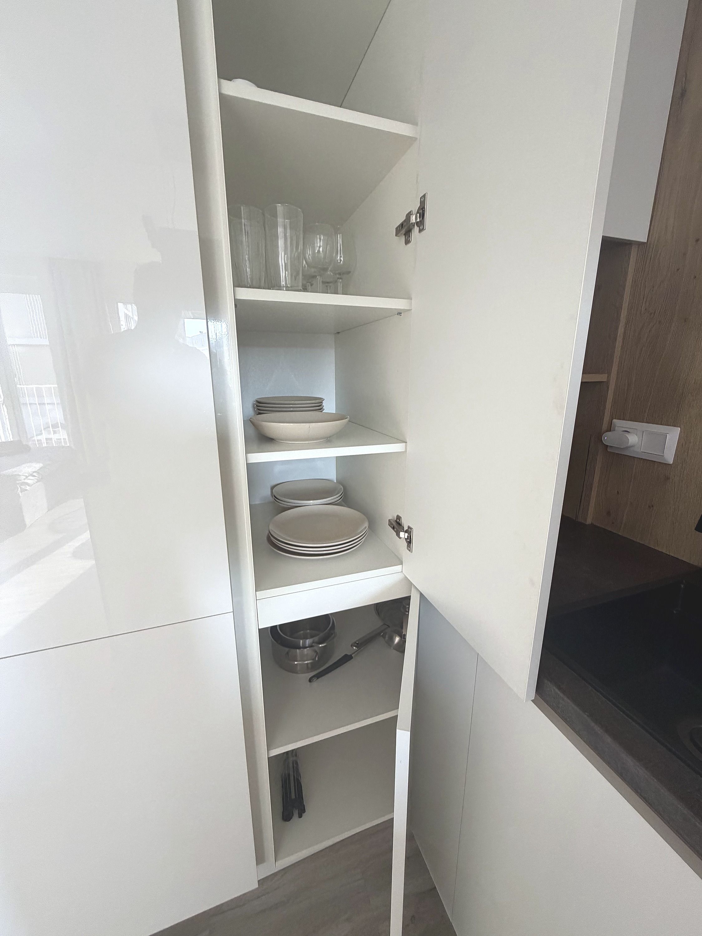 A kitchen with white cabinets, a sink, and a window with a view of the outside.