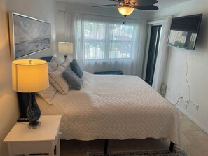 Ein ordentlich eingerichtetes Schlafzimmer mit Bett, Nachttischlampe und Deckenventilator.