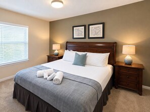 A neatly made bed with a grey bedspread and white pillows, two bedside lamps, a headboard, and a window with blinds. - 3BR Townhome Near Disney Resort Pool Access (Kissimmee)