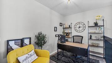 A modern living room with a yellow sofa, a black desk, and a large wall clock.