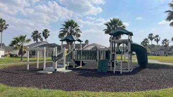 A playground with a slide, climbing structures, and a covered area.