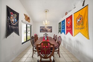 Une salle à manger avec une longue table, des chaises et un lustre.
