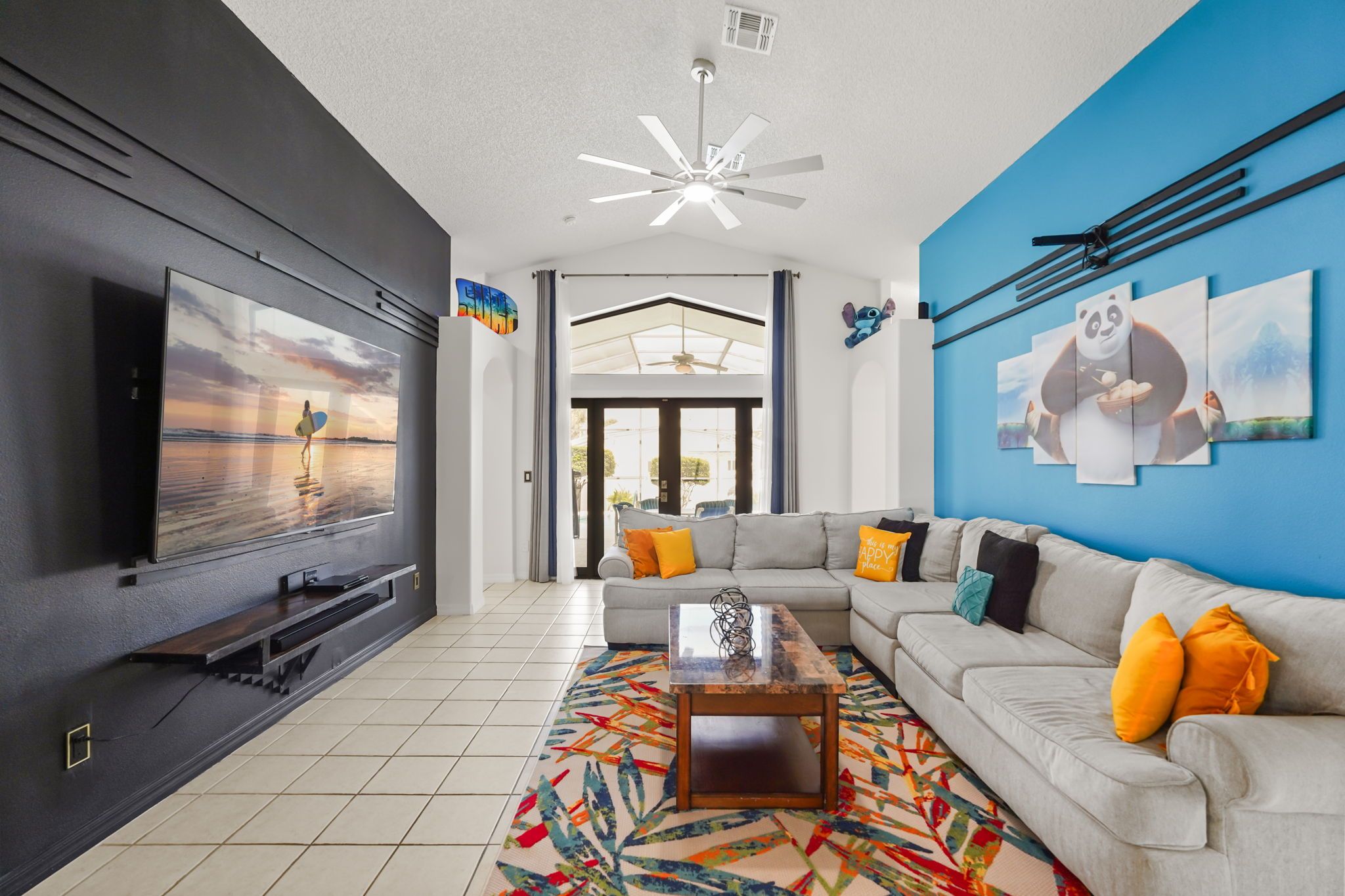 A modern living room with a flat-screen TV, a sectional sofa, a coffee table, and a colorful rug.