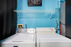 A laundry room with two washing machines, a drying rack, and a wall-mounted sign. - Near Disney + Private Pool 4 BD/ 3BA Indian Creek - 2625 SC (Kissimmee)