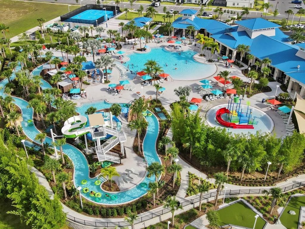 Een luchtbeeld van een resort met verschillende zwembaden, glijbanen en ontspanningszones, omringd door palmbomen.