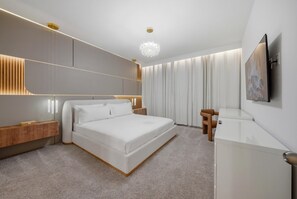 Ein modernes Hotelzimmer mit einem großen Bett, Nachttischen, einem Schreibtisch und einem an der Wand befestigten Flachbildfernseher.