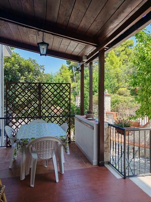 Une terrasse couverte avec une table et des chaises, un plafond en bois et une vue sur la verdure.