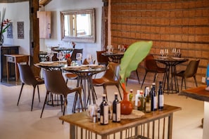 A restaurant interior with round tables, chairs, and a brick wall. - Casa La Torre (Porto Seguro)