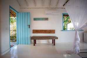 A room with a wooden bench, a blue door, and a window with a view of greenery. - Casa La Torre (Porto Seguro)