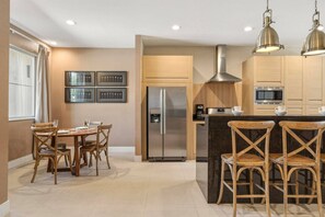 A modern kitchen with a central island, stainless steel appliances, and wooden cabinetry. - 4 Suites Near Disney Balcony & Covered Patio (Kissimmee)