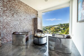 A modern living room with a panoramic city view, a round coffee table, and two leather sofas. - Viewmont Skyterrace By Alora Reserve (Los Angeles)