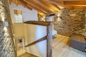 A rustic interior with stone walls, wooden beams, a wooden bench, and a small table. - TWO-BEDROOM PLUS APARTMENT (Castroverde)