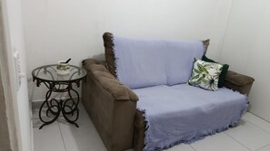 A room with a brown sofa, a small round table, and a white wall. - Betel | Cozy apartment in Copacabana (Rio de Janeiro)