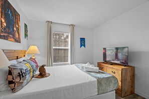 A hotel room with a bed, a television, a wooden dresser, and a window with blinds. - 3BR Near Disney Mickey & Harry Potter Rooms (Kissimmee)