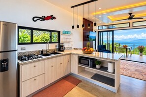 A modern kitchen with a gas stove, microwave, and a view of the outdoors. - Alta Vista: Private 2BR Suite with Mountain & Sunset Views (Alajuela Province, San Ramon)