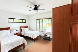 A bedroom with two beds, a ceiling fan, a window with blinds, and a nightstand with a lamp. - Alta Vista: Private 2BR Suite with Mountain & Sunset Views (Alajuela Province, San Ramon)