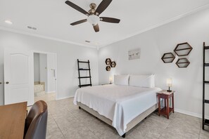 A bedroom with a bed, a desk, and a chair. There is a ceiling fan and a wall-mounted lamp. - Canal-Front Townhome with Private Boat Dock (Corpus Christi)
