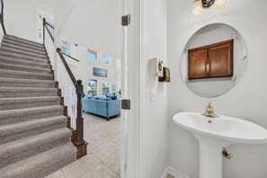 A staircase with a wooden handrail leading to a landing. - Canal-Front Townhome with Private Boat Dock (Corpus Christi)